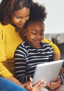 Smiling young mom and cute little daughter watching something funny on tablet 