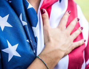 a woman with american flag with her hand on her chest 